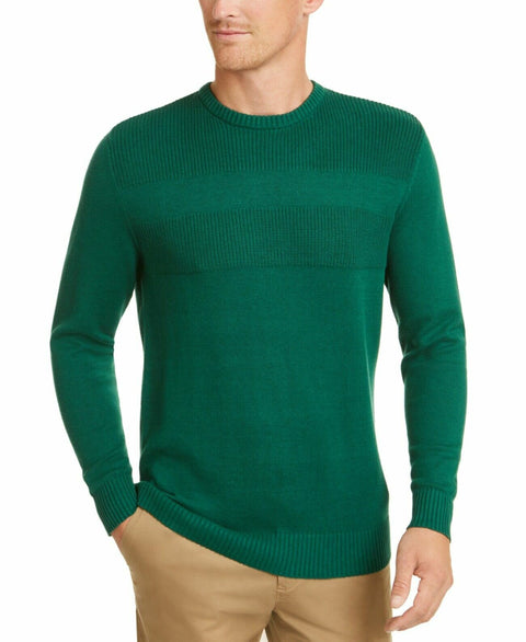 Man wearing a green sweater and beige pants on a white background