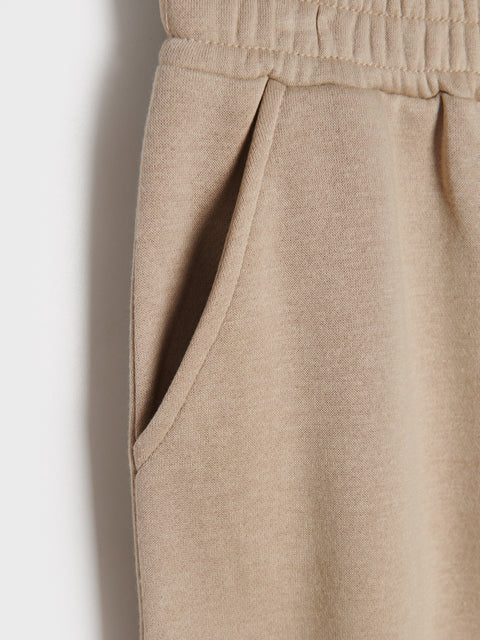 Close-up of beige pants with a plain background