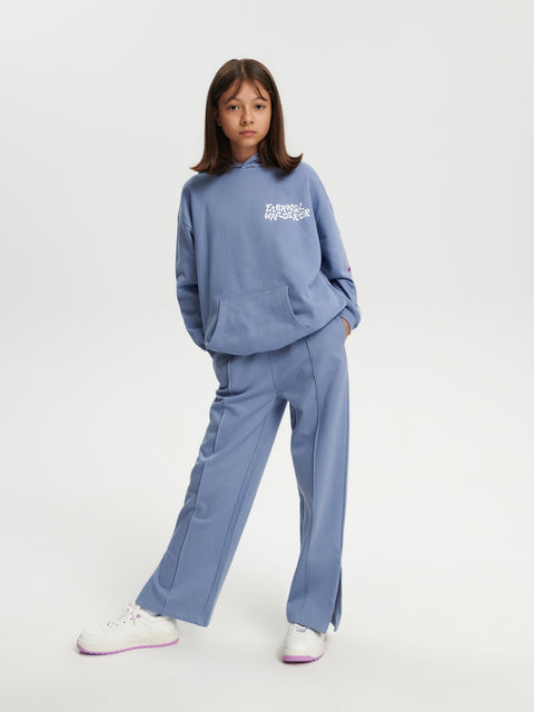 Person wearing a blue tracksuit with a logo on a white background