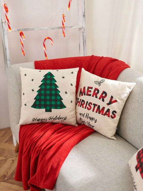 Decorative Christmas pillows on a couch with a red blanket and candy canes in the background.