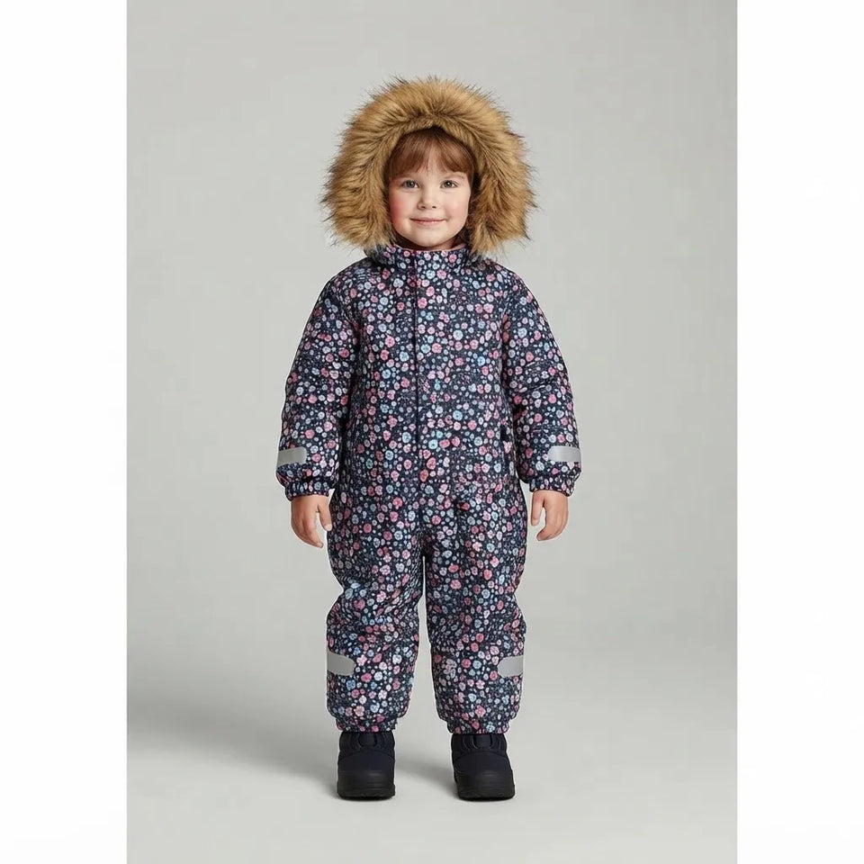 A young child wearing a dark floral snowsuit with a brown faux-fur trimmed hood, standing against a light gray studio background.