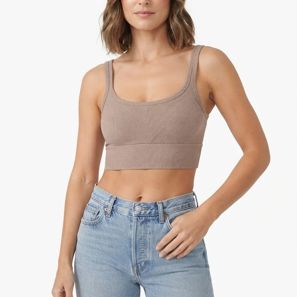 A woman wearing a ribbed scoop-neck crop top in taupe and light-wash blue jeans, shown from the waist up against a plain white background.