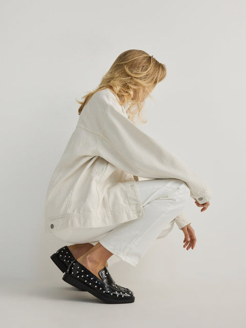 Person wearing a white outfit with black shoes on a plain background