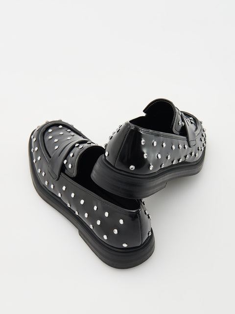 Black studded shoes on a white background