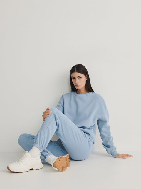 Person wearing a light blue outfit sitting on a white background