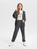 Person wearing a gray tracksuit with a white graphic t-shirt on a white background