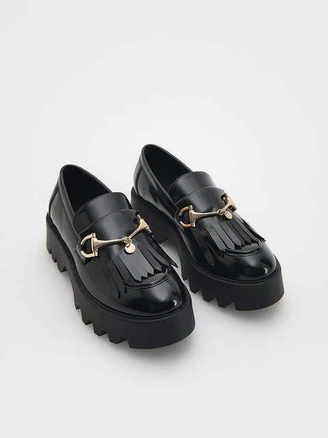 Black platform loafers with gold accents on a light gray background