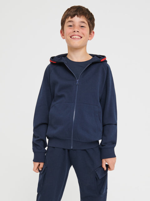 Child wearing a navy blue tracksuit with a red hood on a white background