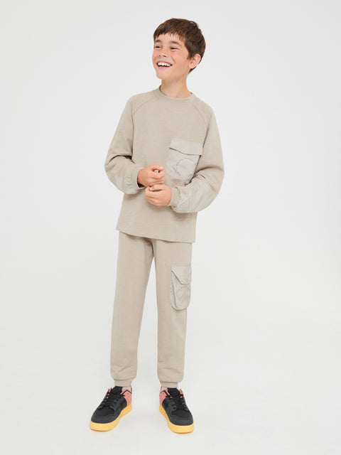 Child wearing a beige outfit with cargo pockets on a white background