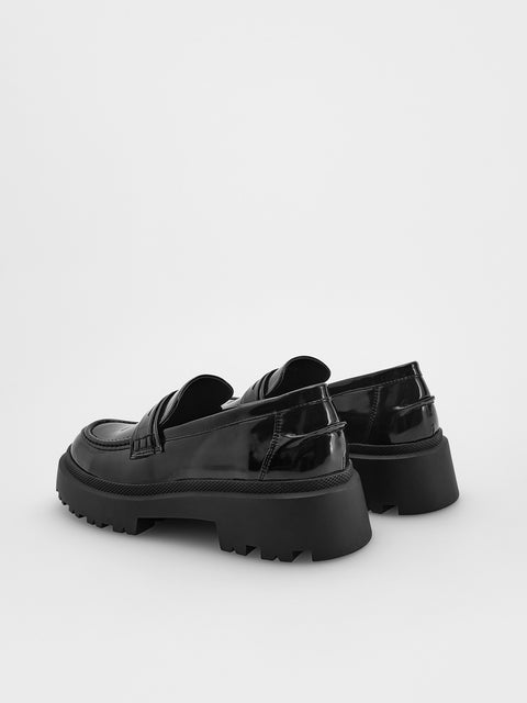 Black platform loafers on a white background