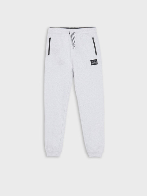 White sweatpants with a small logo on a light gray background