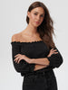 Woman wearing a black off-shoulder top against a plain background