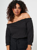 Woman wearing a black off-shoulder top with long sleeves on a white background