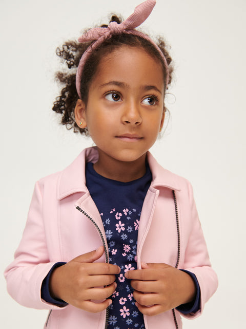 Young girl wearing a pink jacket with a white background