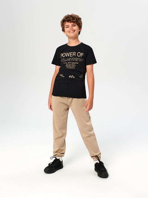 Person wearing a black t-shirt with text and beige pants on a white background