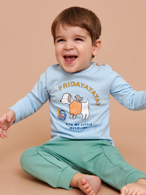 Child wearing a light blue shirt with a dog graphic and text, sitting on a beige background