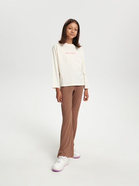 Person wearing a white long-sleeve shirt and brown pants on a white background