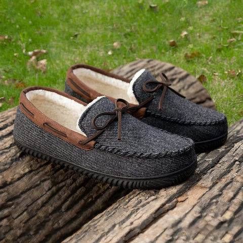 Pair of gray slippers with brown trim on a wooden surface