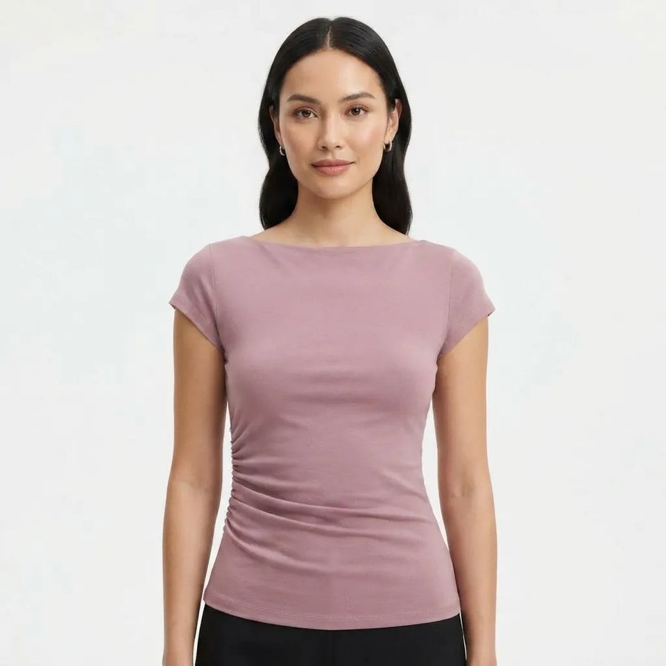 A woman modeling a fitted short-sleeve boat-neck top in a dusty mauve pink color, paired with black bottoms, against a plain light gray background.