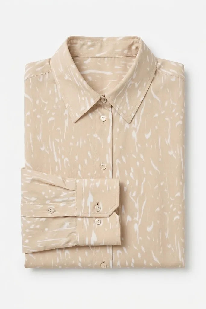 A beige long-sleeve button-up shirt with a white abstract brushstroke pattern, neatly folded on a light gray background.