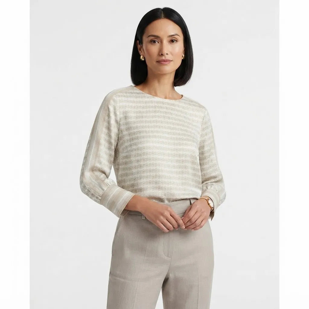 A woman modeling a light beige and white striped knit sweater with three-quarter sleeves, paired with light beige trousers, against a plain light gray background.
