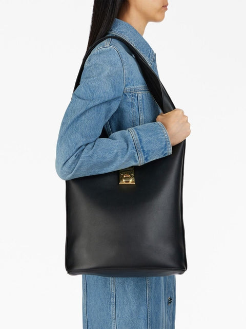 Person wearing a black leather bag over one shoulder on a white background