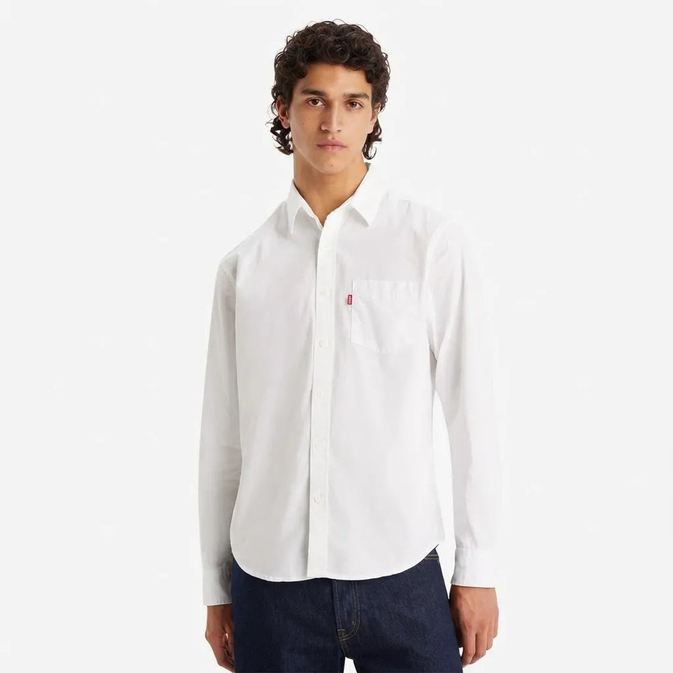 A man wearing a white long-sleeve button-down shirt with a chest pocket and a small red Levi's tag, paired with dark blue jeans, against a plain white background.