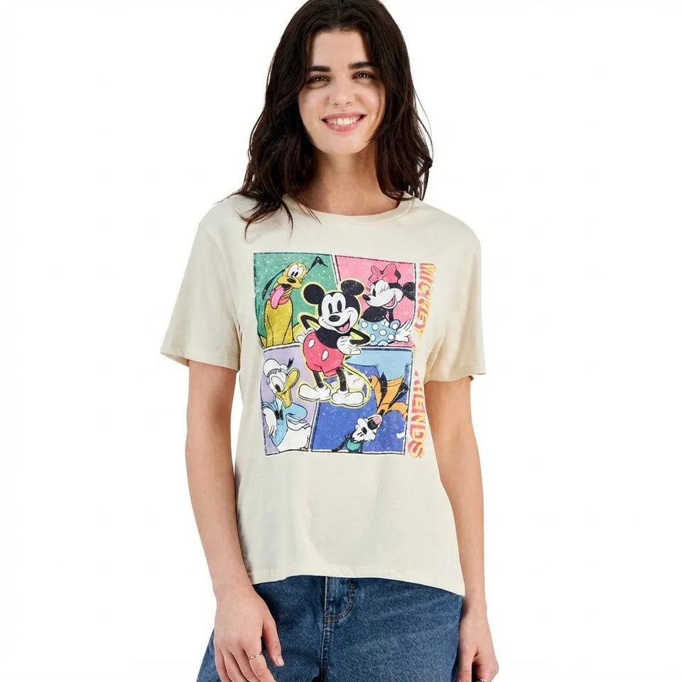 A woman modeling a beige graphic t-shirt featuring Disney characters in a comic-style print on the front, paired with blue jeans against a plain white background.