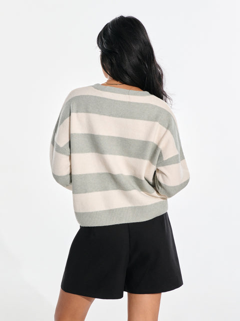 Person wearing a striped sweater and black shorts on a white background