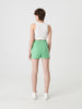 Person wearing a white sleeveless top and green shorts on a white background