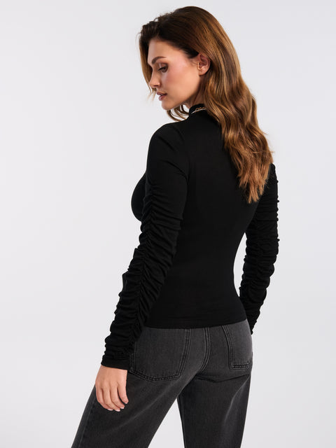 Woman wearing a black long-sleeve top and gray pants on a white background