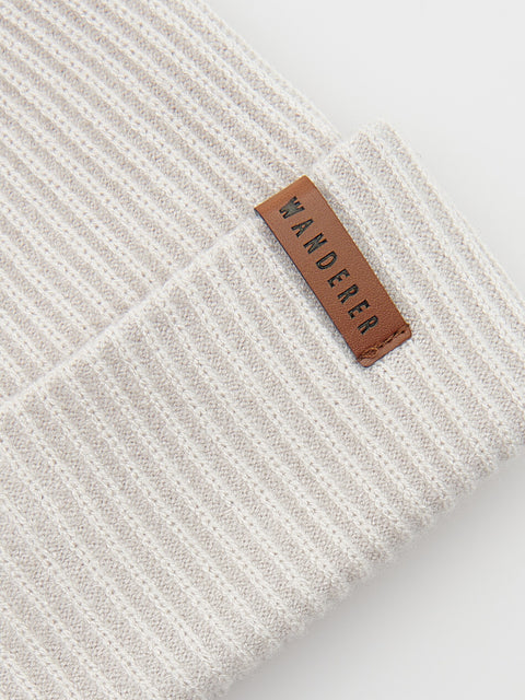 Close-up of a textured white fabric with a brown leather label reading 'Wanderer' on a light gray background.