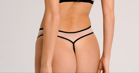 Woman wearing a black lingerie set on a plain background