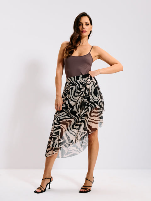 Woman wearing a patterned skirt and brown top on a white background