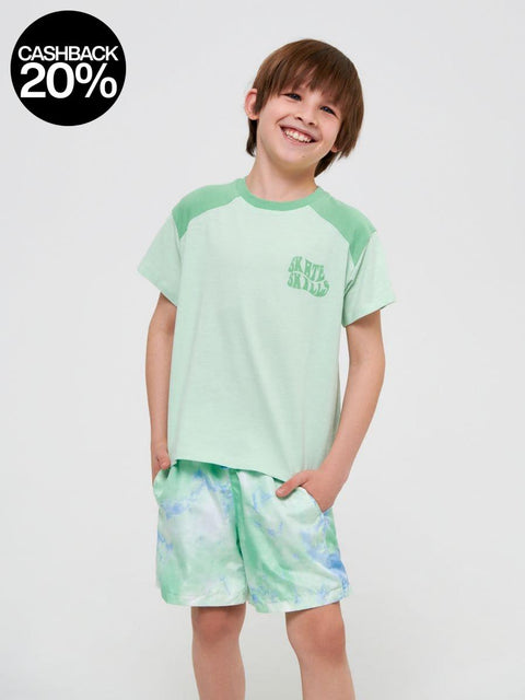 Child wearing a green t-shirt and shorts with a logo on a white background