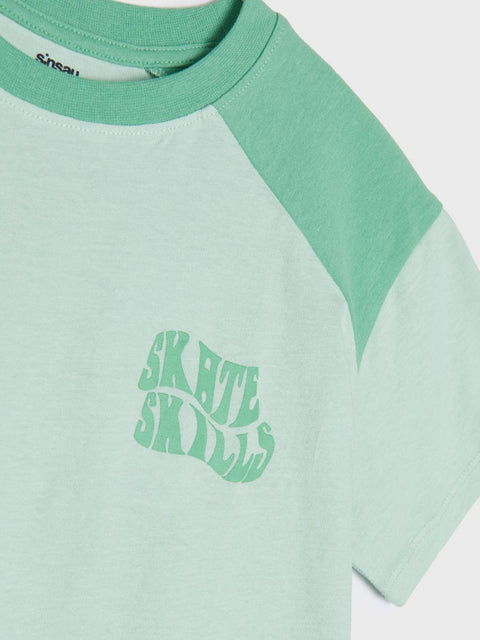 Green and white t-shirt with 'Skate Skills' text on a light gray background