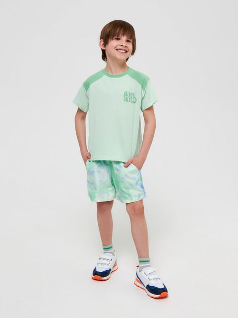 Child wearing a green and white outfit with shorts on a white background