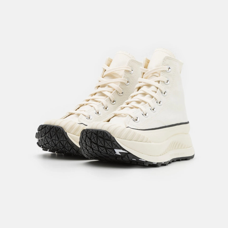 A pair of off-white high-top lace-up sneakers with black textured soles, shown from a three-quarters angle on a light gray background.