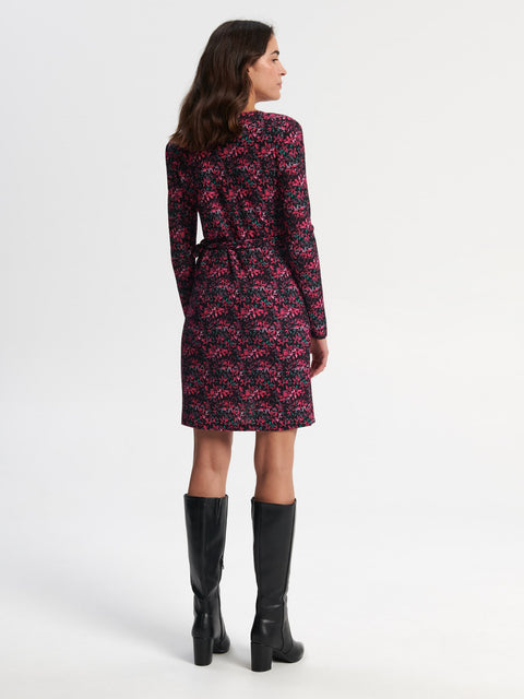 Woman wearing a floral dress with long sleeves and black boots on a white background