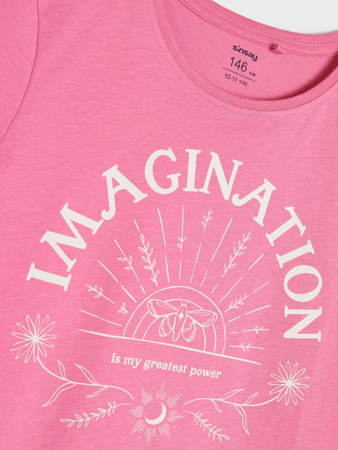Pink t-shirt with 'IMAGINATION is my greatest power' text and graphics on a plain background