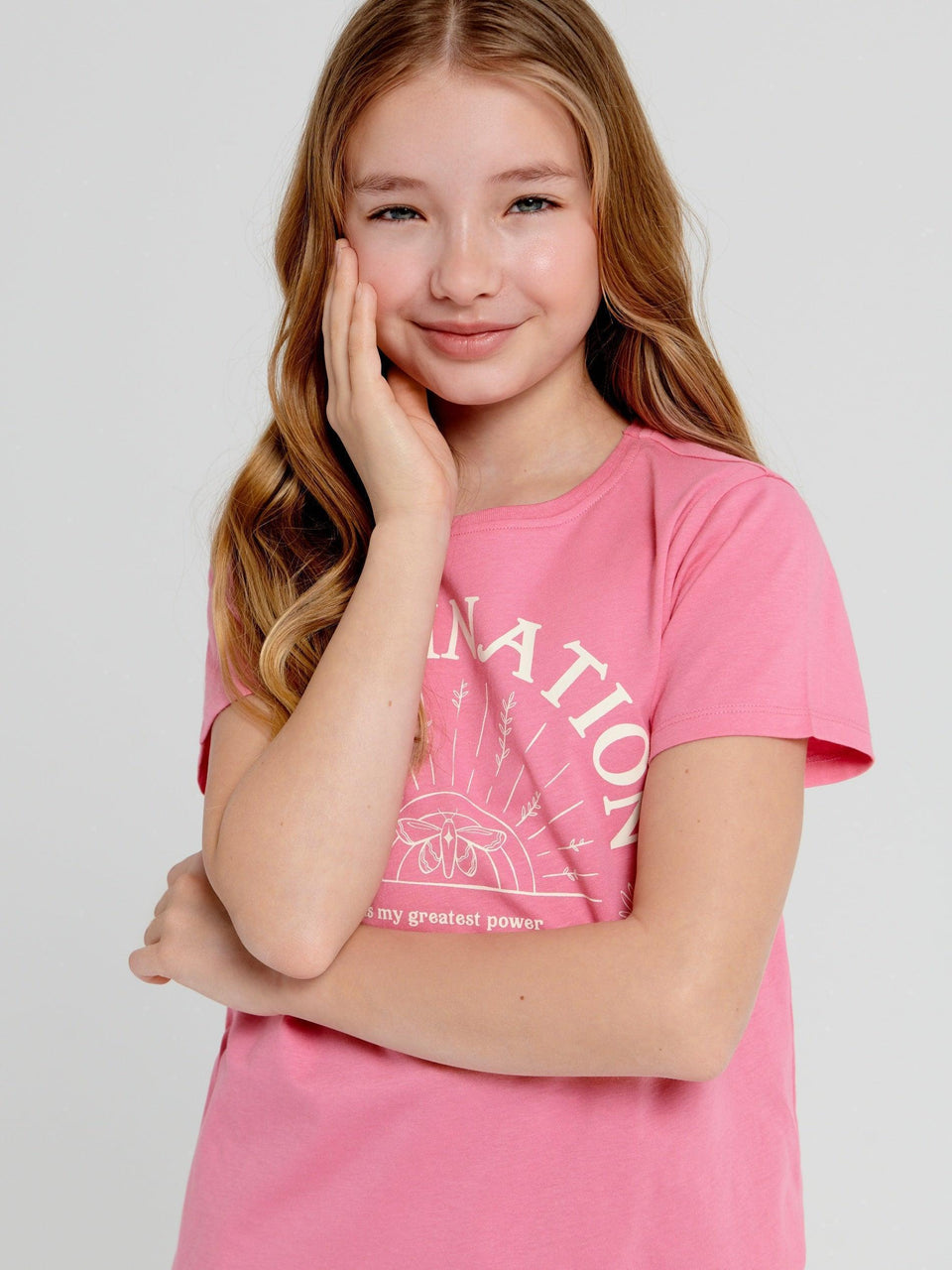 Young girl wearing a pink t-shirt with text on a plain background