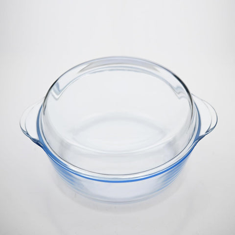 Clear glass cooking pot with lid on a light gray background