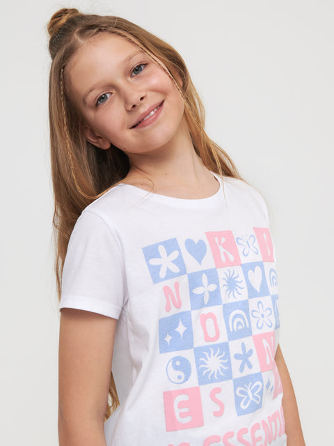 Young girl wearing a white t-shirt with colorful geometric patterns on a plain background