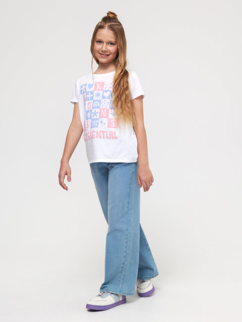 Young girl wearing a white t-shirt with colorful graphics and blue jeans on a white background