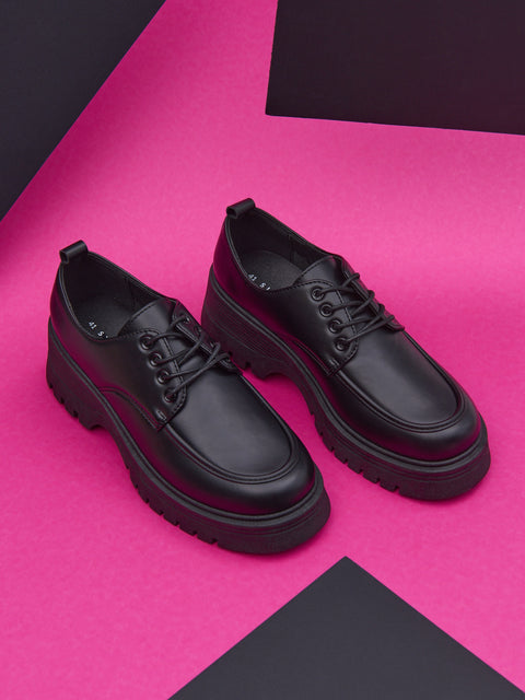 Black leather shoes on a pink and black geometric background