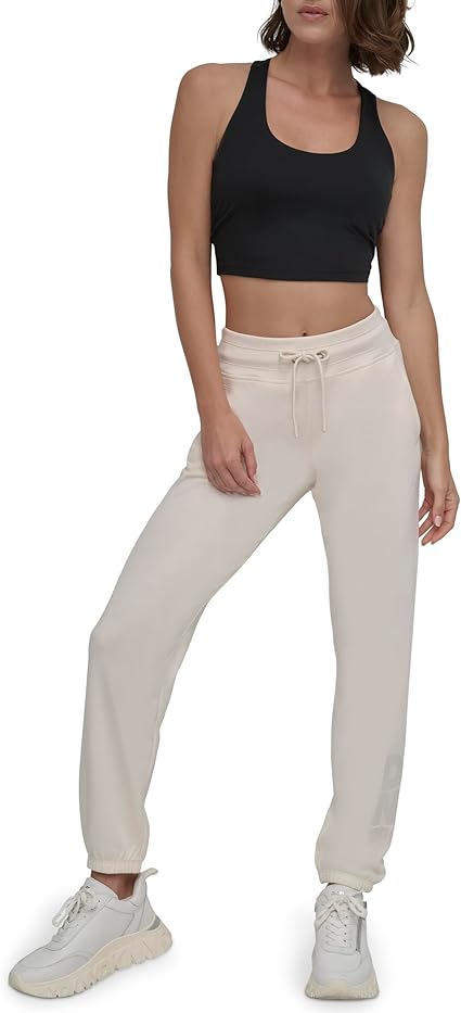 Woman wearing a black crop top and beige pants on a white background