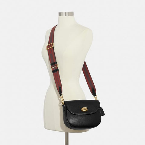 Black handbag with red strap on a mannequin against a white background