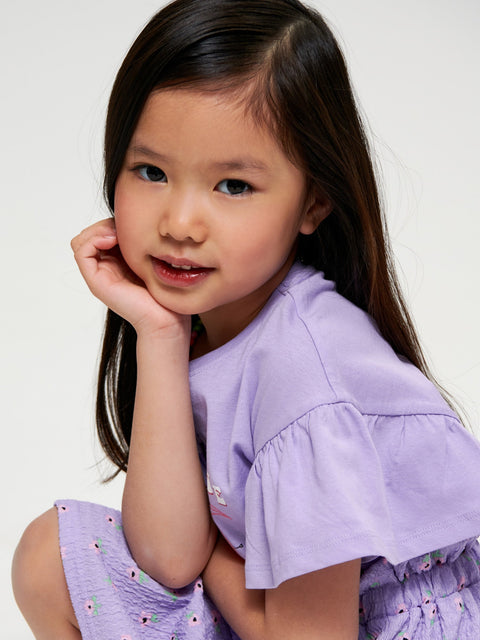 Young girl wearing a purple dress against a white background