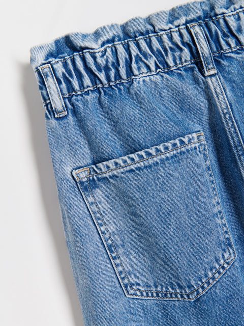Close-up of blue denim shorts with a pocket on a light gray background