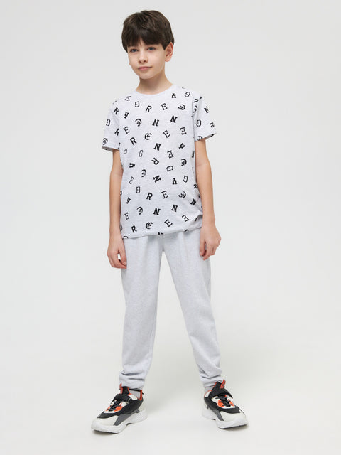 Child wearing a white t-shirt with black patterns and gray pants on a white background